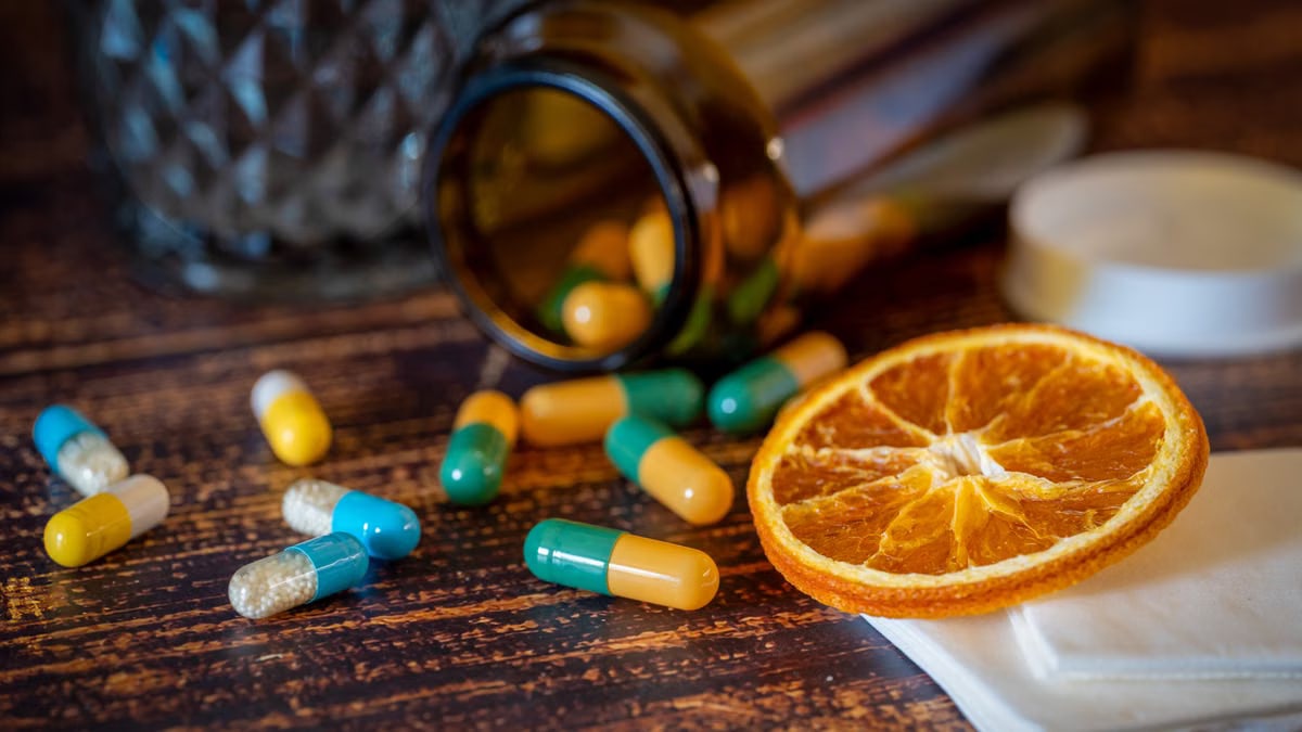 Close-up of vitamins, pills, and dried orange slice for cold relief.